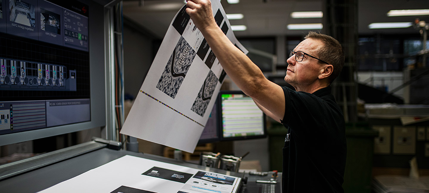 vår filosofi – trykker holder opp ark og ser på detaljer